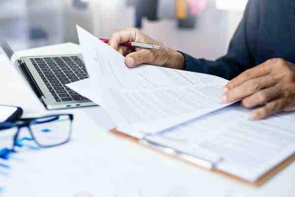 Person mit Dokumenten und Laptop